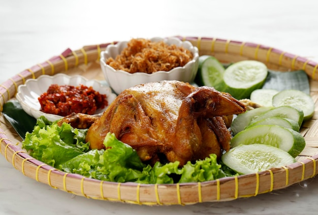 Ayam Goreng Utuh Frittiertes ganzes Hühnchen, serviert mit Sambal-Chili-Paste und frischem Gemüse