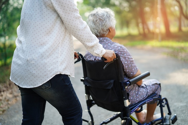 Ayuda y atención a anciana o anciana asiática anciana mujer paciente sentada en silla de ruedas