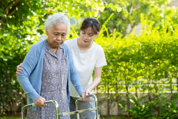 Ayuda y cuidado del cuidador La anciana o anciana asiática usa un andador con buena salud mientras camina en el parque en felices vacaciones frescas