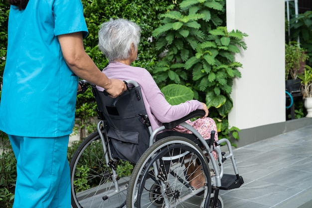 Ayuda y cuidado del cuidador Paciente asiática mayor o anciana anciana sentada en silla de ruedas a la rampa