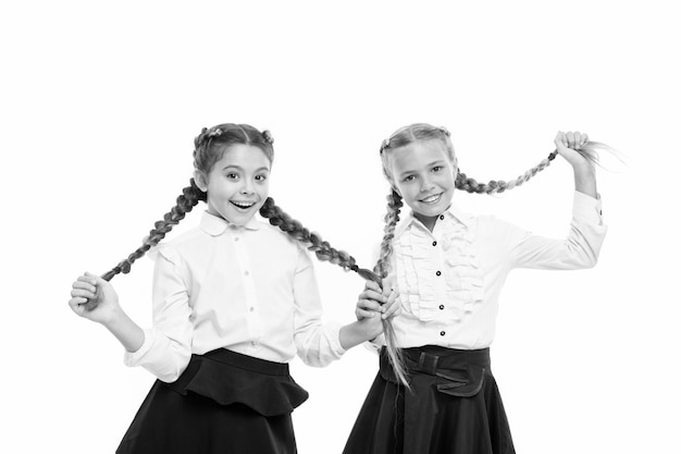 Ayudando a que el cabello crezca más rápido Adorables niños pequeños cuidando el cabello largo Linda niña pequeña sosteniendo trenzas de cabello largo aisladas en blanco Usando cabello largo en trenzas para la escuela