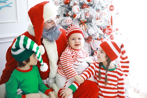 Ayudantes de Santa Claus Lindos niños disfrazados de duende navideño en una habitación bellamente decorada para Navidad. Tiempo de milagros. Regalos de Santa Claus.