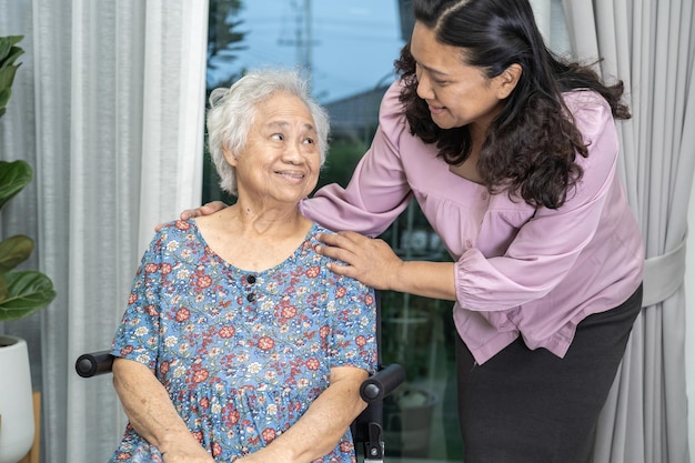 Ayudar y cuidar a una anciana o anciana asiática sentada en silla de ruedas en el hospital de enfermería con un concepto médico fuerte y saludable