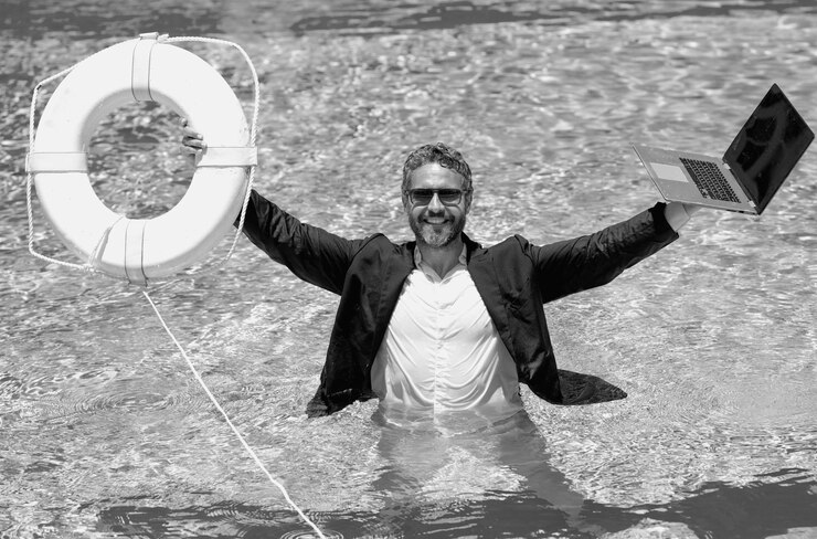 Foto ayudar a los negocios el hombre de negocios en traje sostiene la computadora portátil y ayuda a la boya salvavidas en la piscina el rescate ayuda a nadar en el agua para el hombre de negocios ayudar a las empresas ahorrar y ayudar a las empresas ayudar y rescatar