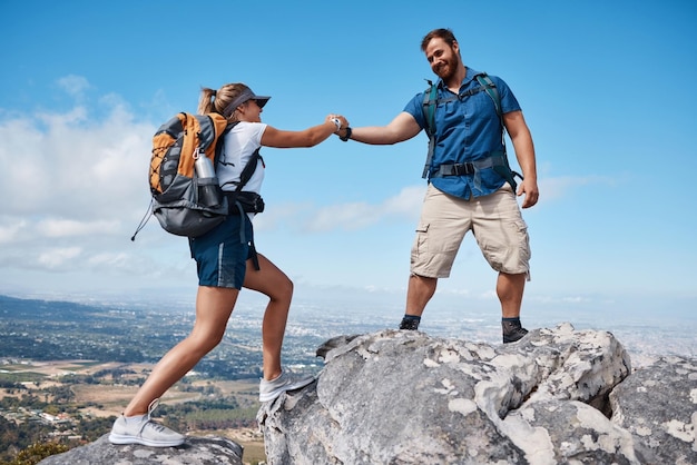 Ayudar a una pareja o amigos a hacer senderismo en la montaña en la naturaleza con una sonrisa o entrenar Aventura de viaje y entrenamiento de trekking hombre y mujer en un campo al aire libre o ejercicio y apoyo de escalada en roca