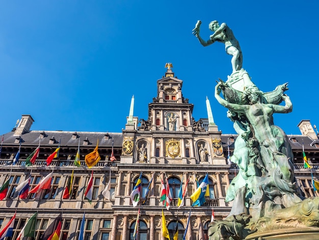 Ayuntamiento y fuente Brabo en la Gran Plaza del Mercado de Amberes, Bélgica, bajo un cielo azul claro