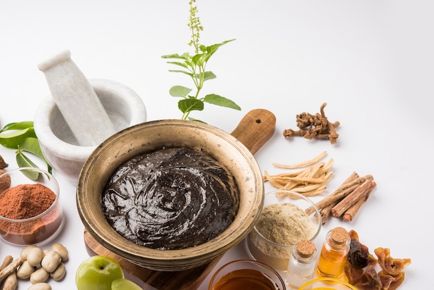 Ayurvedic Chyawanprash é um poderoso impulsionador da imunidade ou suplemento natural para a saúde. Servido em uma tigela antiga com ingredientes, sobre fundo sombrio, foco seletivo