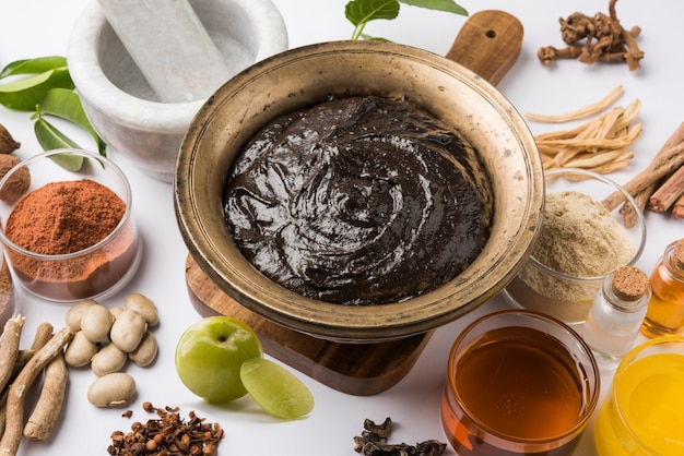 Ayurvedisches Chyawanprash ist ein leistungsstarker Immunitätsverstärker oder ein natürliches Nahrungsergänzungsmittel. Serviert in einer antiken Schüssel mit Zutaten, über stimmungsvollem Hintergrund, selektiver Fokus