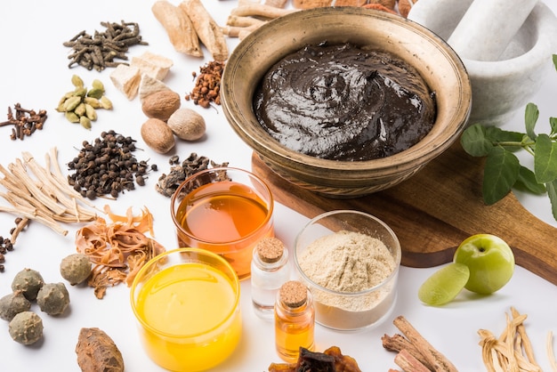 Ayurvedisches Chyawanprash ist ein leistungsstarker Immunitätsverstärker oder ein natürliches Nahrungsergänzungsmittel. Serviert in einer antiken Schüssel mit Zutaten, über stimmungsvollem Hintergrund, selektiver Fokus