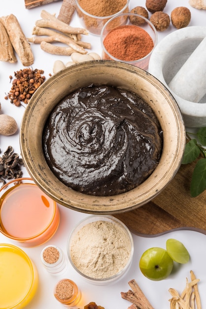 Ayurvedisches Chyawanprash ist ein leistungsstarker Immunitätsverstärker oder ein natürliches Nahrungsergänzungsmittel. Serviert in einer antiken Schüssel mit Zutaten, über stimmungsvollem Hintergrund, selektiver Fokus