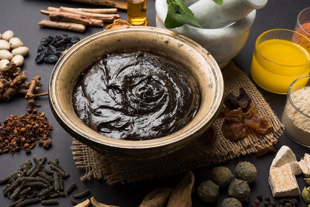 Ayurvedisches Chyawanprash ist ein leistungsstarker Immunitätsverstärker oder ein natürliches Nahrungsergänzungsmittel. Serviert in einer antiken Schüssel mit Zutaten, über stimmungsvollem Hintergrund, selektiver Fokus