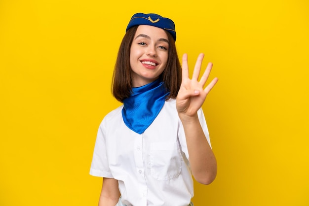 Azafata de avión Mujer ucraniana aislada de fondo amarillo feliz y contando cuatro con los dedos