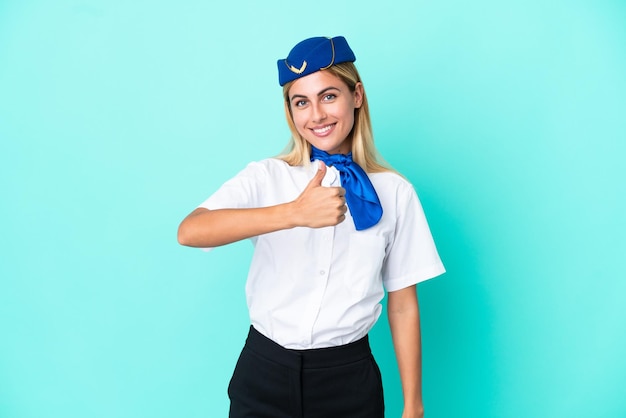 Azafata de avión mujer uruguaya aislada de fondo azul dando un gesto de pulgar hacia arriba