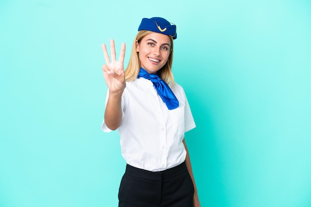 Azafata de avión mujer uruguaya aislada de fondo azul feliz y contando tres con los dedos