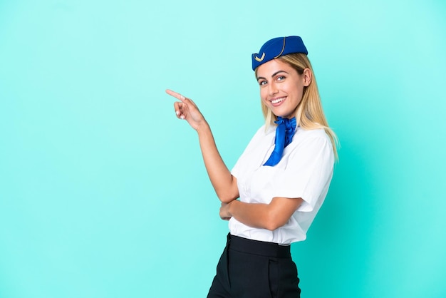 Azafata de avión mujer uruguaya aislada de fondo azul señalando con el dedo al lado