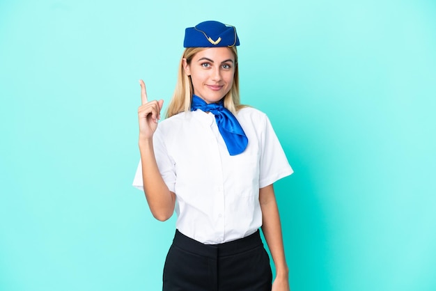 Azafata de avión Mujer uruguaya aislada de fondo azul señalando con el dedo índice una gran idea
