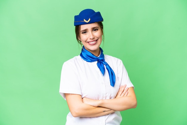 Azafata de avión sobre fondo clave de croma aislado con los brazos cruzados y mirando hacia adelante