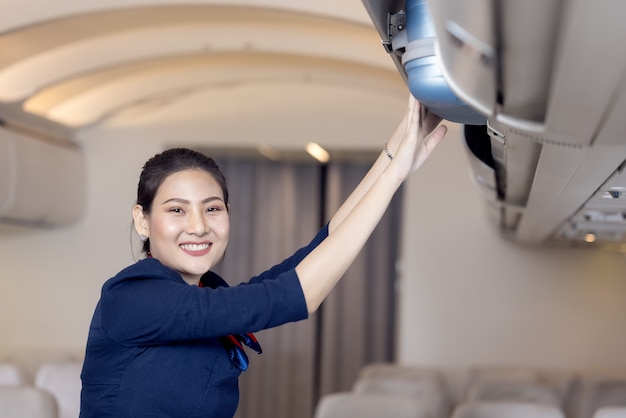 La azafata ayuda a los pasajeros a poner su equipaje en la cabina del avión. Azafata en el avión.