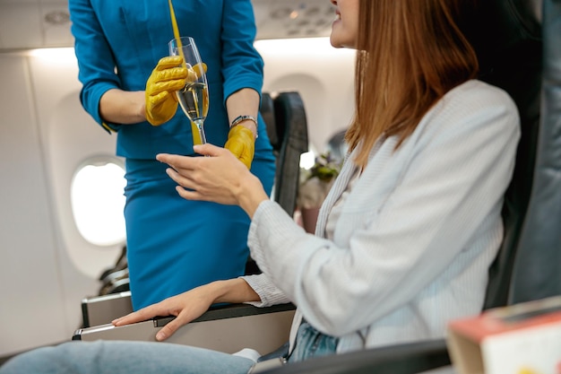 Azafata dando champán a mujer en avión de pasajeros