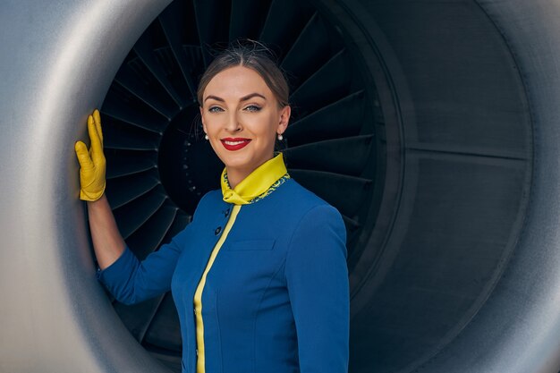 Foto azafata encantadora apoyando su mano enguantada sobre el motor turbofan