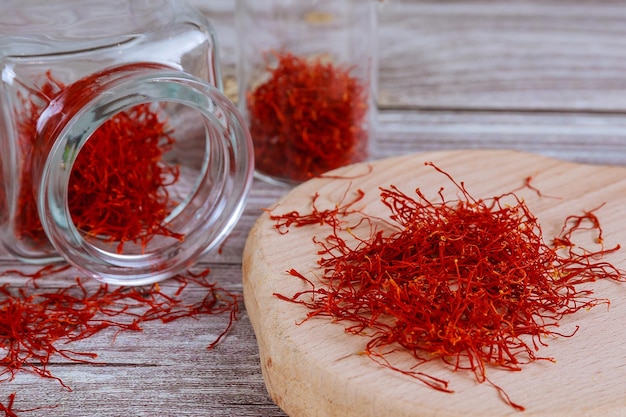 Foto azafrán seco sobre una tabla de madera en una botella de vidrio estambres rojos de azafrán sativus