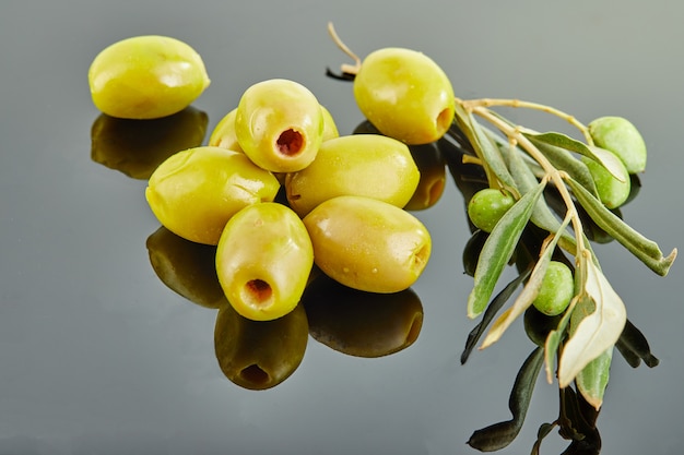 Azeitonas com um ramo de uma oliveira com frutas, deitado em um slide sobre um fundo cinza