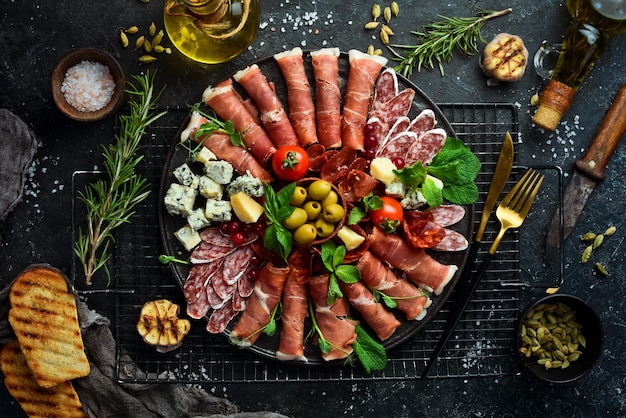 Azeitonas de queijo parmesão de porco seco de presunto italiano e petiscos em um prato Vista superior Em um fundo de pedra cinza