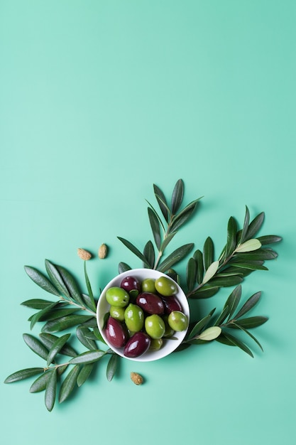 Azeitonas frescas e galho de oliveira em uma mesa