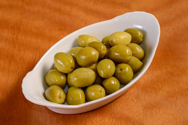 Azeitonas pequena porção de azeitonas em recipiente branco na mesa de madeira