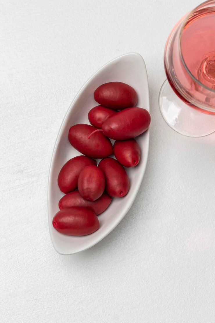 Foto azeitonas vermelhas em uma tigela branca um copo de vinho tinto