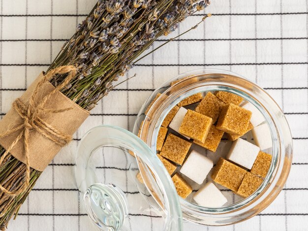 Azúcar en un azucarero transparente y un ramo de lavanda sobre la mesa