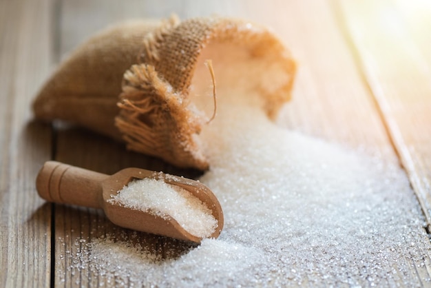 Azúcar blanco para alimentos y dulces postres dulces montón de azúcar dulce azúcar granulado cristalino en saco y fondo de madera