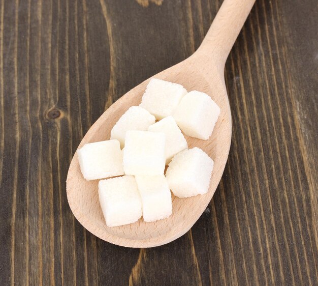 Azúcar blanco en cuchara sobre fondo de madera