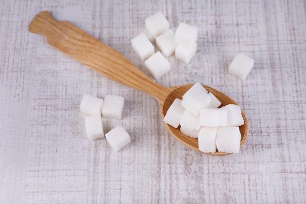 Azúcar blanco refinado en cuchara de madera sobre fondo de madera