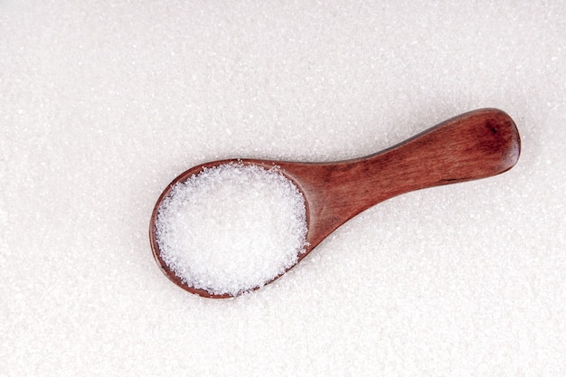 Azúcar blanco con vista superior de fondo de cuchara de madera