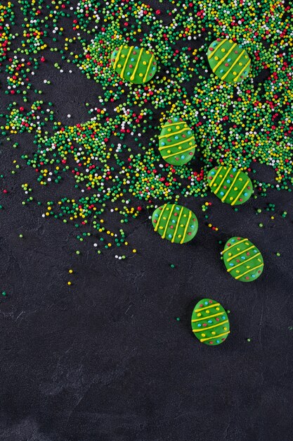 El azúcar espolvorea los puntos y los huevos verdes del caramelo de azúcar, decoración para la torta de pascua y panadería, como fondo. En negro