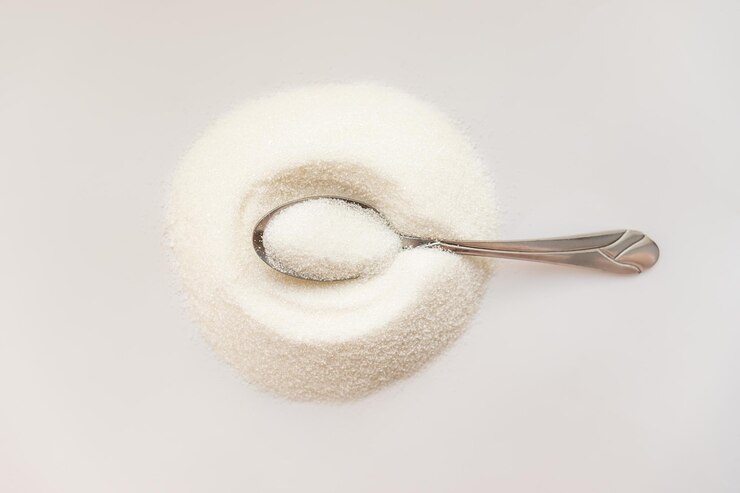 Foto azúcar en un fondo blanco en una cuchara de metal vista superior de la cuchara metálica daño o beneficio del azúcar blanco