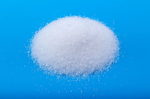 Azúcar granulada blanca sobre un fondo azul.