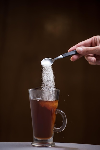 Azúcar en movimiento entrando en una taza con té dulce desayuno