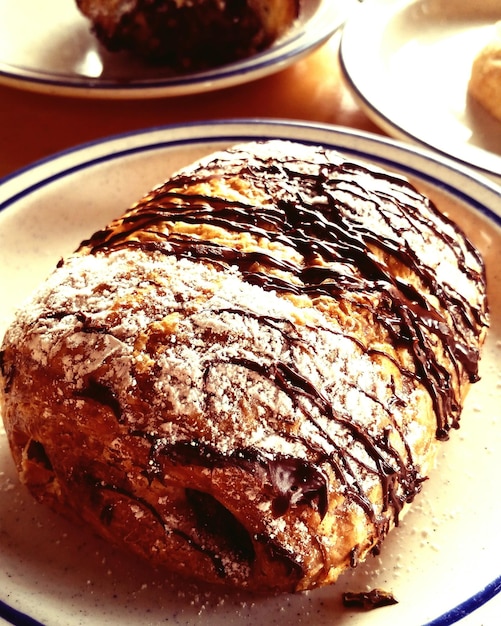 Azúcar en polvo en croissants de chocolate en el plato