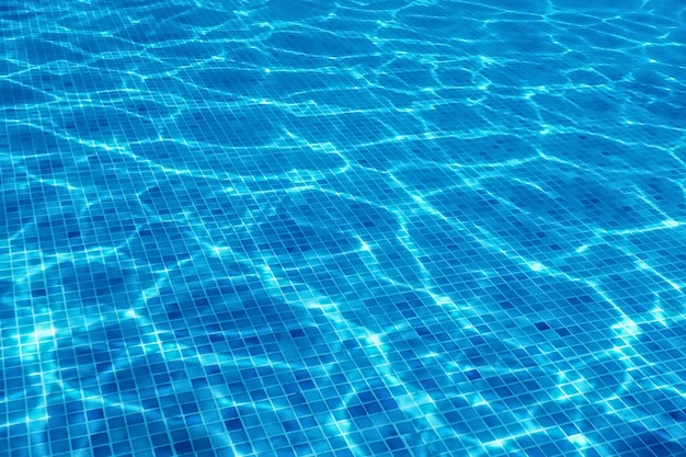 Azulejo azul da piscina subaquática, ondulações na água da piscina