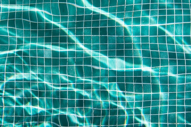 Foto azulejos azuis da piscina, reflexos do sol na água da piscina de cima.