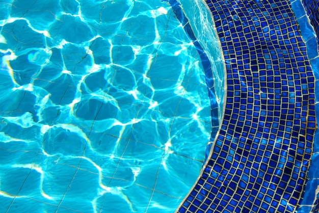 Azulejos azuis de jacuzzi na piscina azul água e efeito de reflexão da luz solar