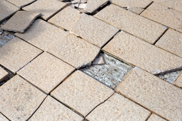 Azulejos marrones agrietados en el piso de cemento