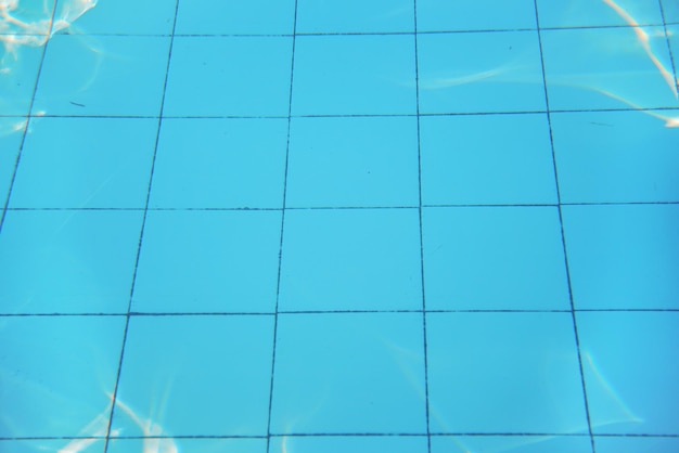 Azurblauer Swimmingpool, alter Fliesenboden, Sonne spiegelt sich auf dem Boden, Unterwasserfoto - abstrakter Urlaubshintergrund