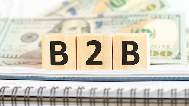 Foto b2b. b2b, abreviatura de empresa a empresa. concepto de negocio sobre fondo de cubos de madera y dólares