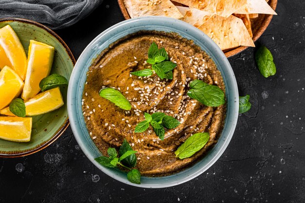 Baba ganoush aperitivo oriental tradicional con semillas de sésamo y primer plano de hojas de menta. Hummus de berenjena con croquetas de pita.