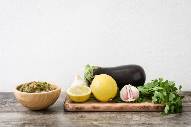 Baba ganoush e ingrediente en un tazón de madera en la mesa de madera