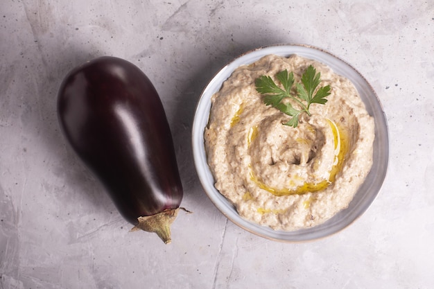 Baba Ganoush Levantinische Küche Vorspeise aus gebackenen Auberginen und Sesampaste mit Kräutern und Olivenöl auf Betonhintergrund