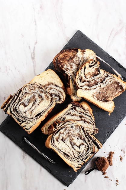 Babka de chocolate o pan brioche. Pastelería dulce del desierto casera - Pan de remolino de chocolate con textura de mármol. En rodajas sobre fondo blanco.